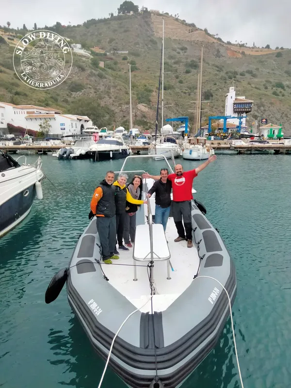 Groupe de plongeurs souriants à bord d'un bateau pneumatique gris