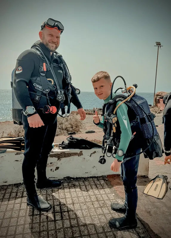 Deux plongeurs équipés sourient, prêts pour une immersion en mer