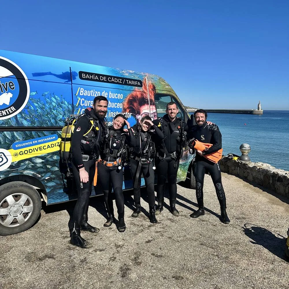 Groupe de plongeurs équipés devant un van décoré sur une plage