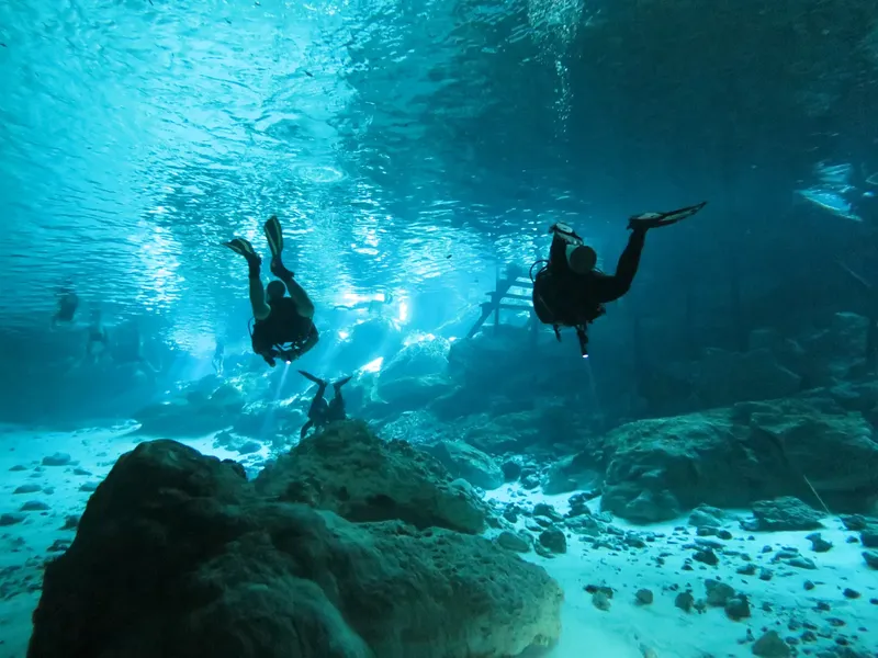 Plongeurs explorent une grotte sous-marine avec une lumière bleutée