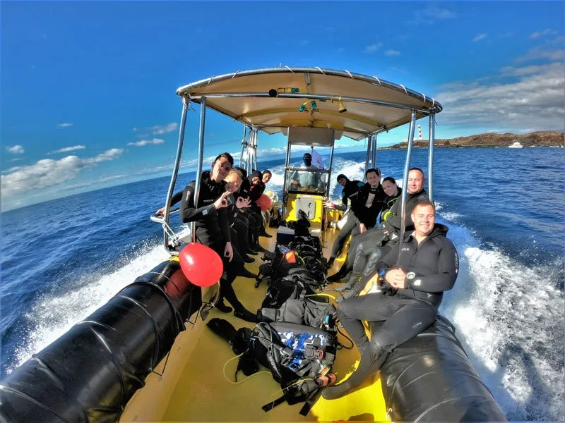 Groupe de plongeurs en combinaison sur un bateau jaune en mer