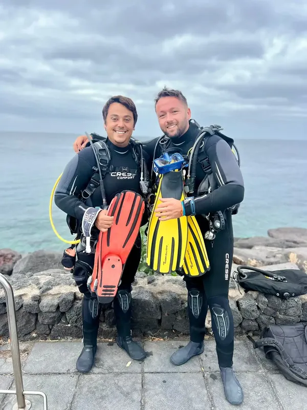 Deux plongeurs souriants équipés, prêts pour une exploration marine