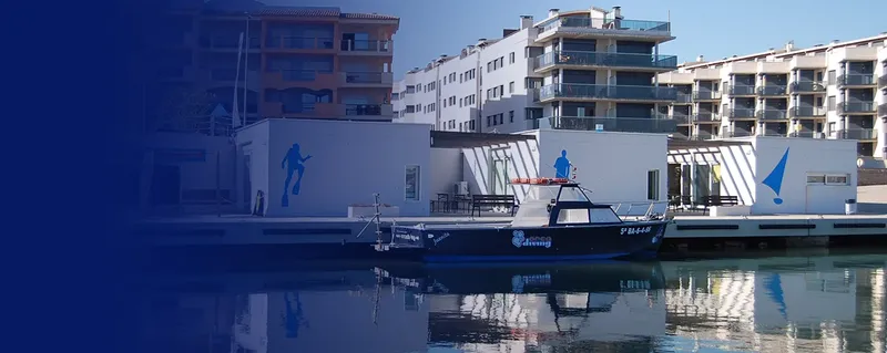 Bateau de plongée amarré devant les bâtiments du centre de plongée