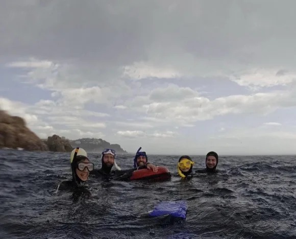 Groupe de personnes souriantes en combinaison de plongée dans la mer