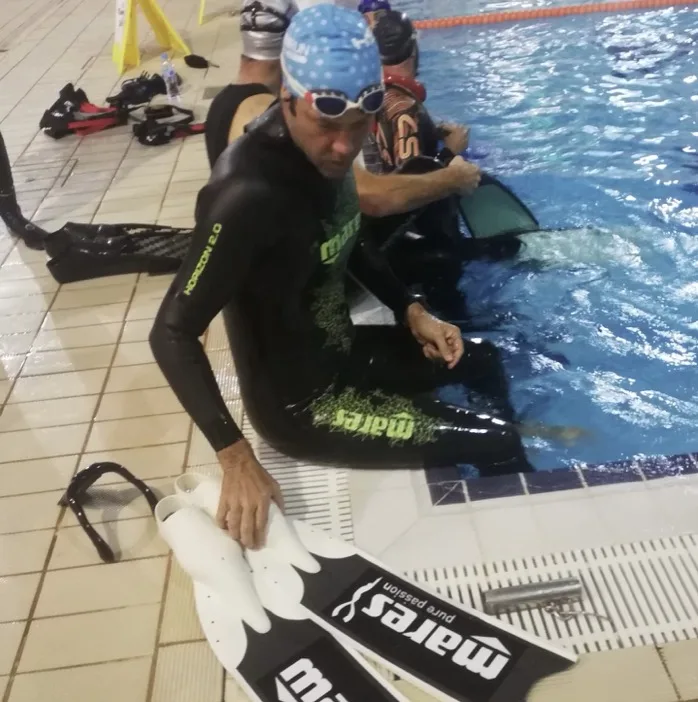 Deux plongeurs s'entraînent en piscine, équipés de combinaisons et de masques