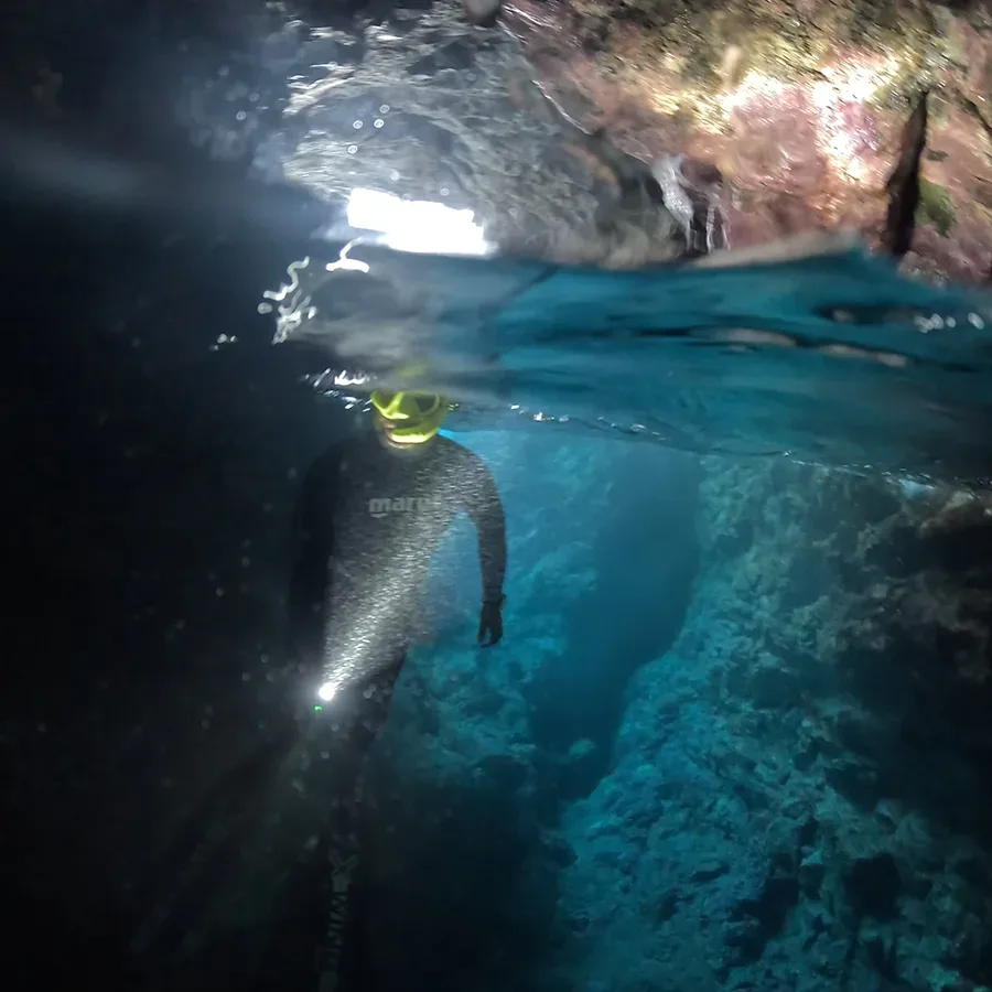 Plongeur en combinaison noire explore une grotte sous-marine éclairée