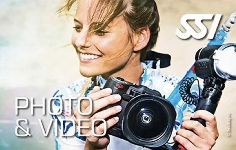 Jeune femme souriante avec appareil photo et équipement de plongée