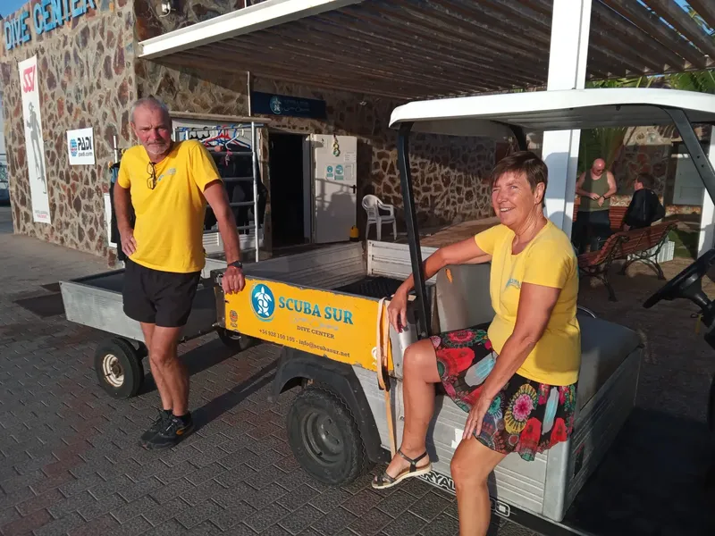 Deux personnes souriantes sur un véhicule électrique devant un centre