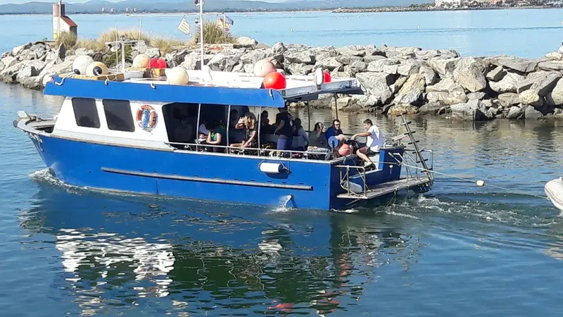 Bateau bleu avec des plongeurs à bord naviguant sur l'eau calme