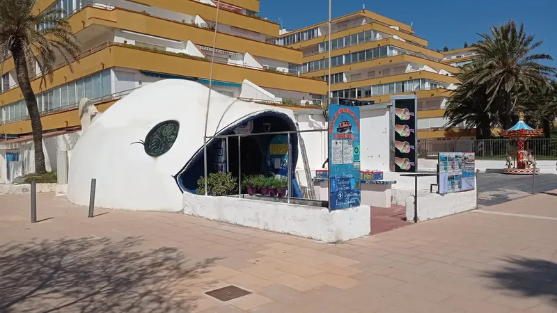 Façade d'un centre de plongée en forme de poisson avec affiches