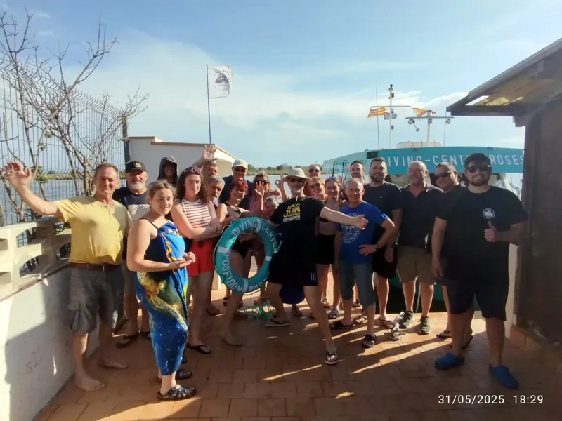 Groupe de plongeurs souriants devant le centre et un bateau