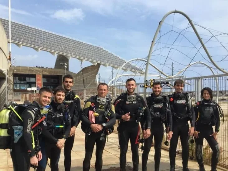 Groupe de plongeurs équipés posant devant une structure architecturale moderne