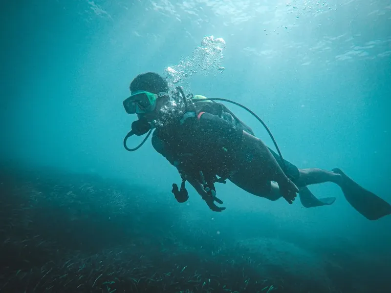 Plongeur en scaphandre nageant dans une eau turquoise et claire