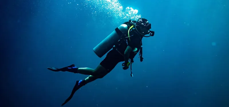 Plongeur en combinaison explore les profondeurs bleues de l'océan