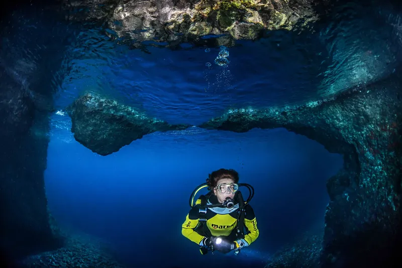 Plongeur explore une grotte sous-marine avec équipement complet et lampe
