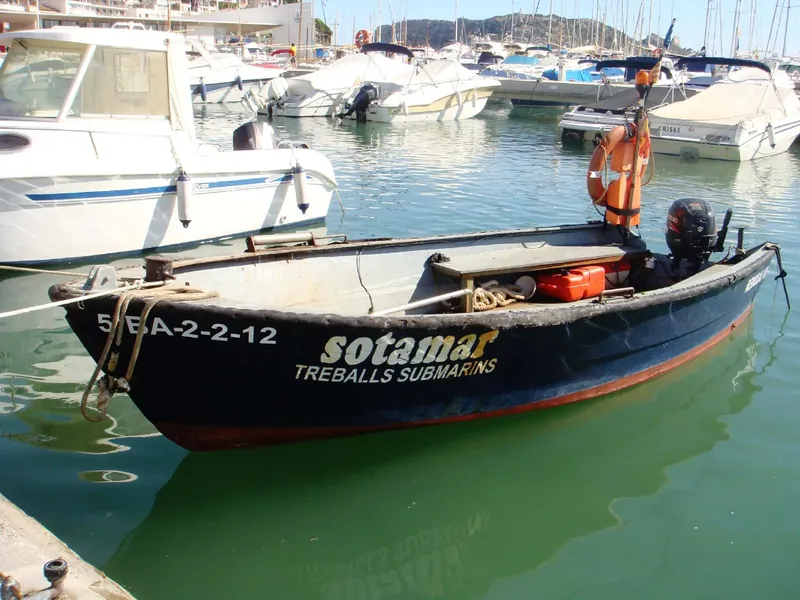 Bateau de plongée noir et rouge amarré dans un port ensoleillé