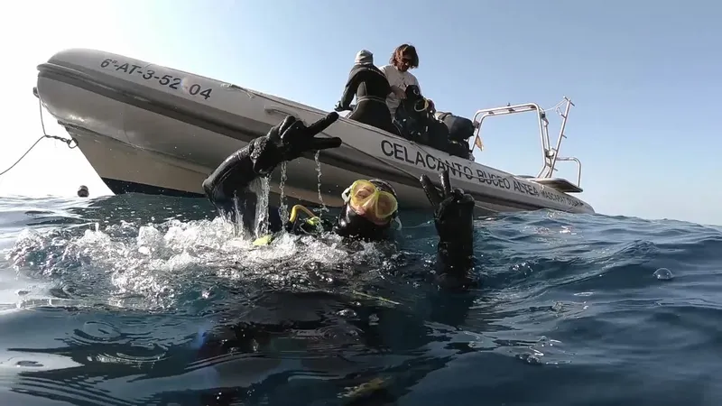 Plongeurs entrant dans l'eau depuis un bateau pneumatique bleu