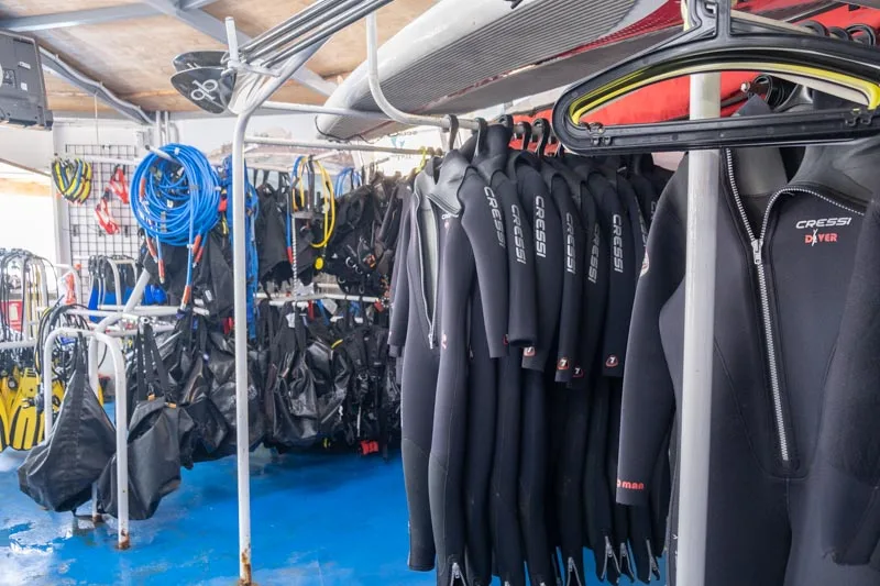Rangées de combinaisons de plongée noires suspendues sur des cintres métalliques
