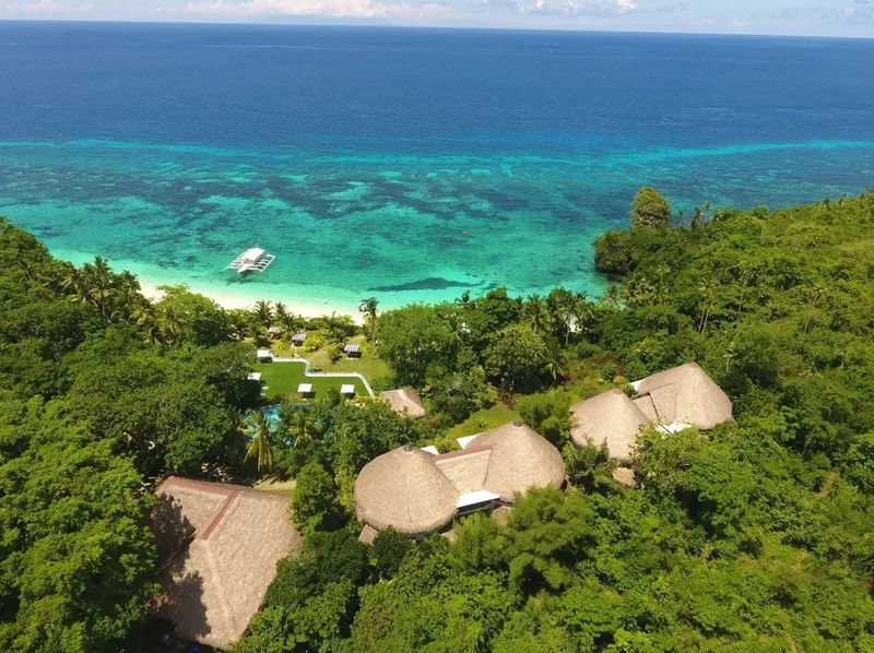 Vue aérienne d'une plage tropicale avec des bungalows et un bateau