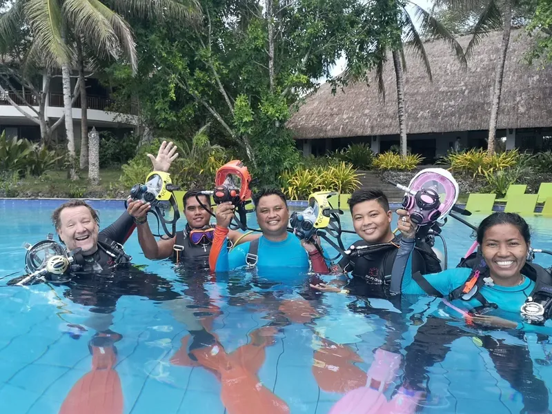 Groupe de plongeurs souriants dans une piscine avec leur équipement