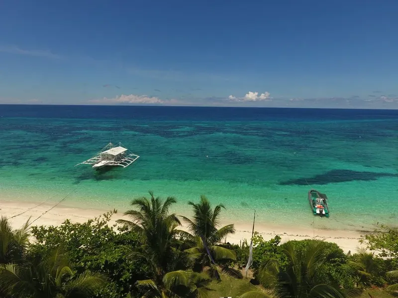 Plage tropicale avec deux bateaux amarrés dans une eau turquoise claire