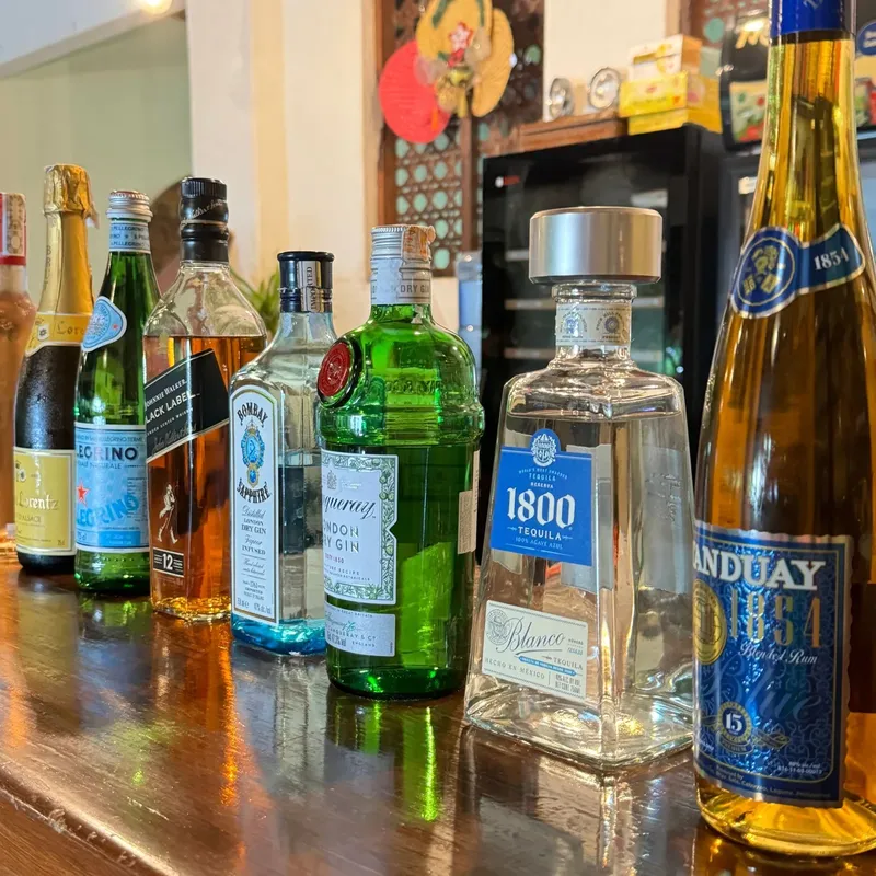 Collection de bouteilles d'alcool colorées sur une étagère en bois