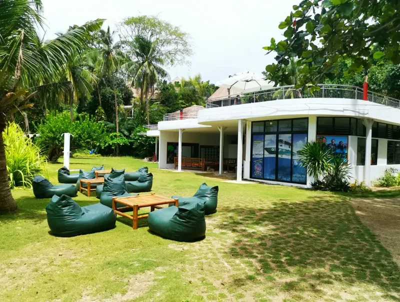 Bâtiment blanc avec mobilier de jardin sur pelouse verdoyante ensoleillée