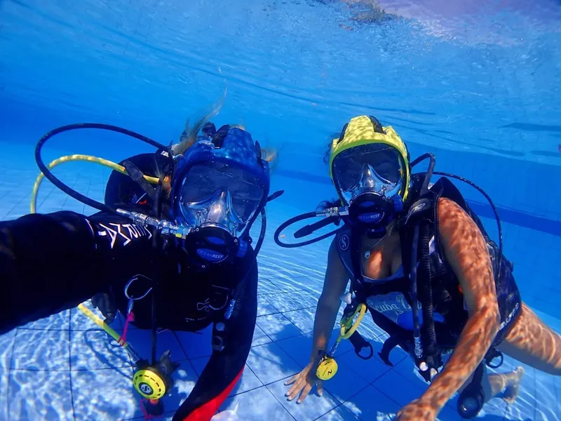 Deux plongeurs souriants en combinaison et masque sous l'eau