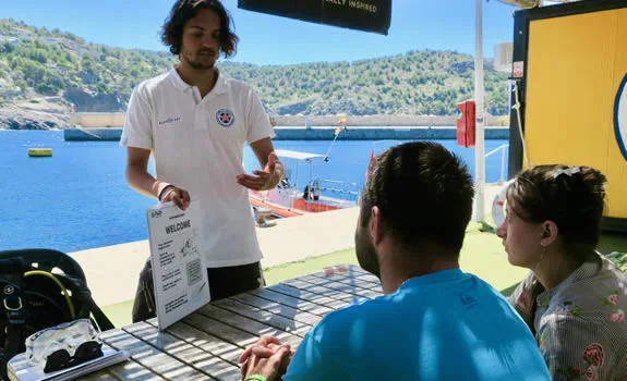 Un moniteur explique un document à deux plongeurs sur un quai