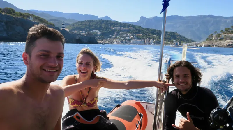 Trois personnes souriantes sur un bateau en mer, paysage côtier