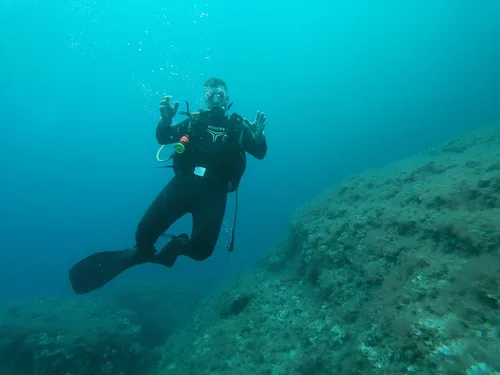 Plongeur en combinaison noire nageant dans une eau bleu clair