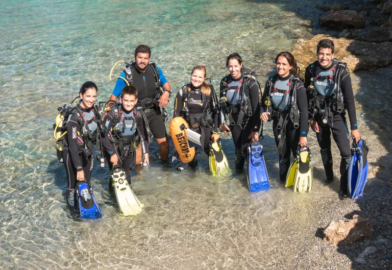 Groupe de plongeurs en combinaison sur une plage de galets
