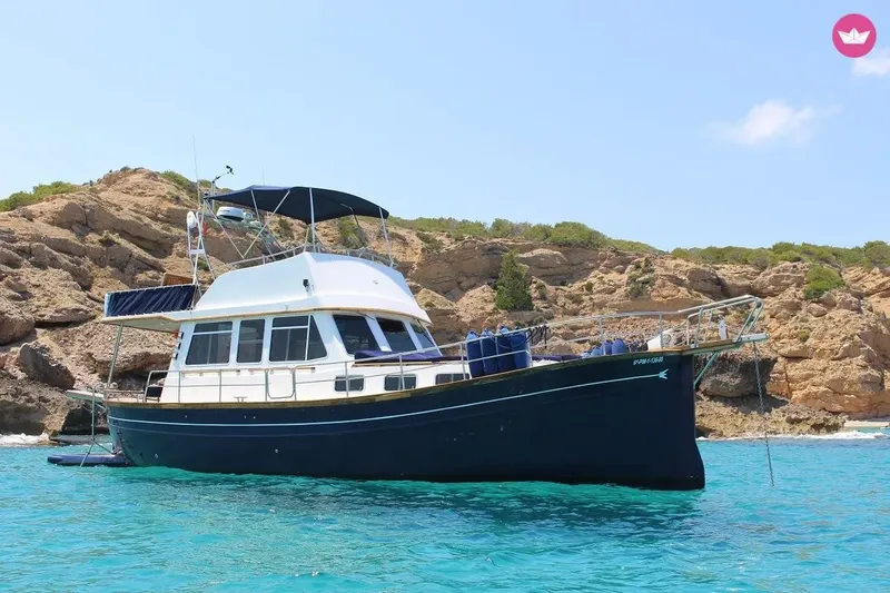 Bateau de plongée bleu et blanc amarré dans une crique turquoise