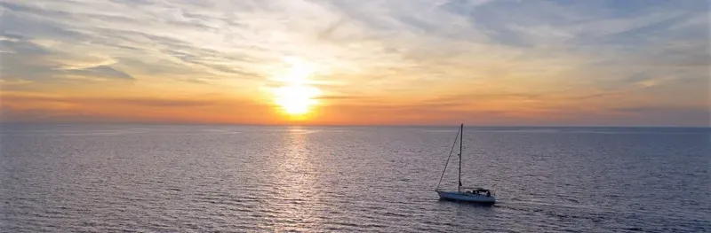 Voilier solitaire sur une mer calme au coucher du soleil