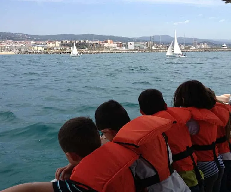 Groupe de personnes regardant des voiliers en mer depuis un bateau