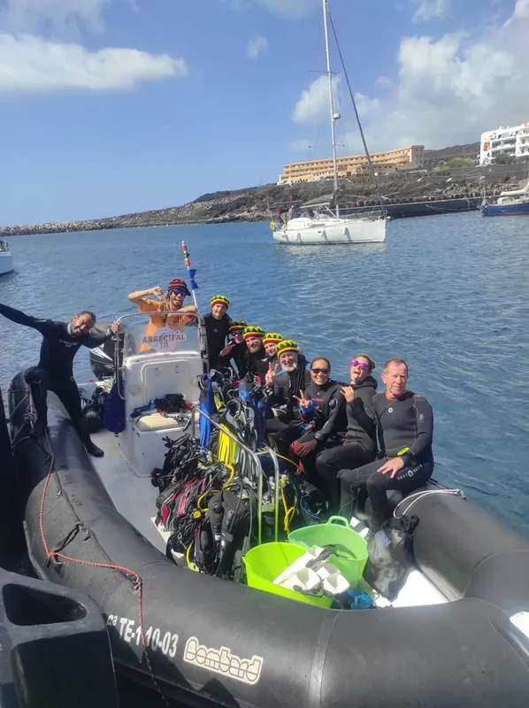 Groupe de plongeurs souriants à bord d'un bateau pneumatique noir