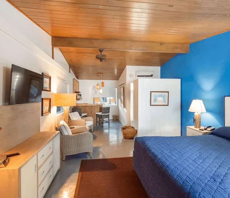 Chambre d'hôtel lumineuse avec coin salon et lit bleu décoré