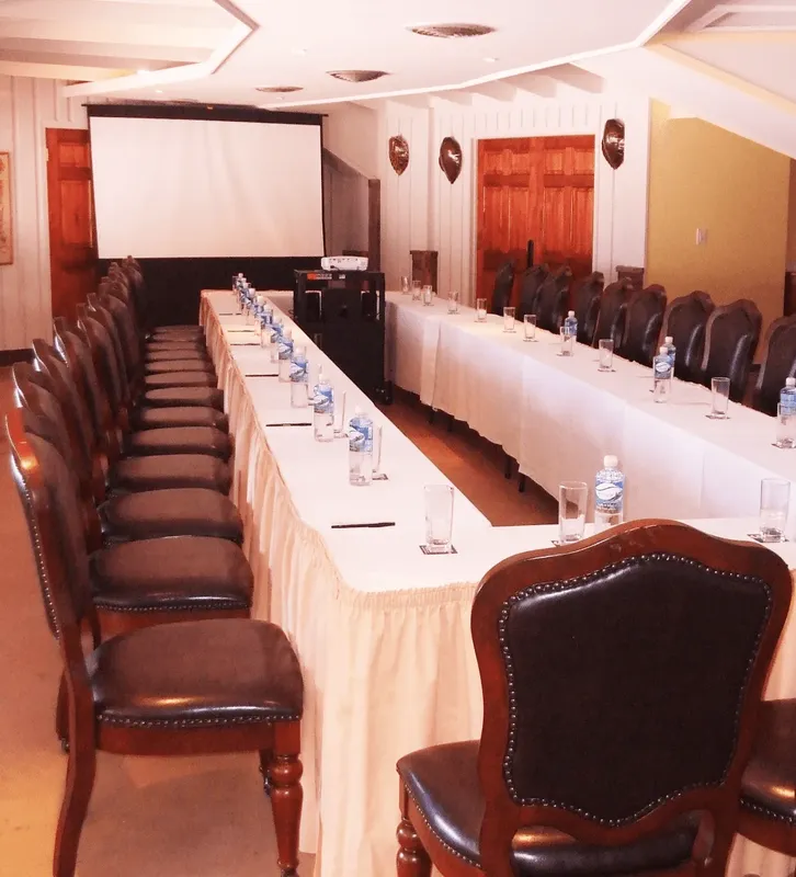 Salle de réunion avec une longue table, des chaises et un écran