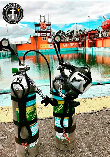 Bouteilles de plongée et masque devant un bateau orange et un quai