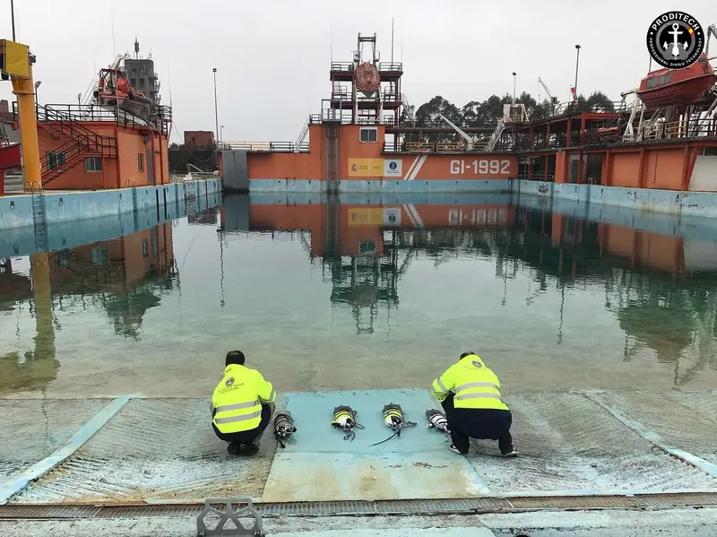 Deux personnes manipulent du matériel près d'une grande piscine d'entraînement