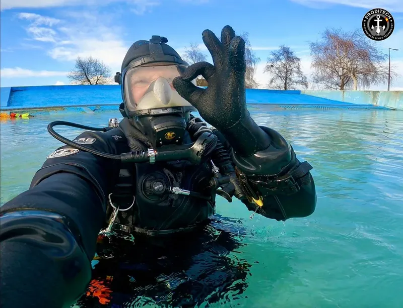 Plongeur en combinaison noire fait un signe OK sous l'eau