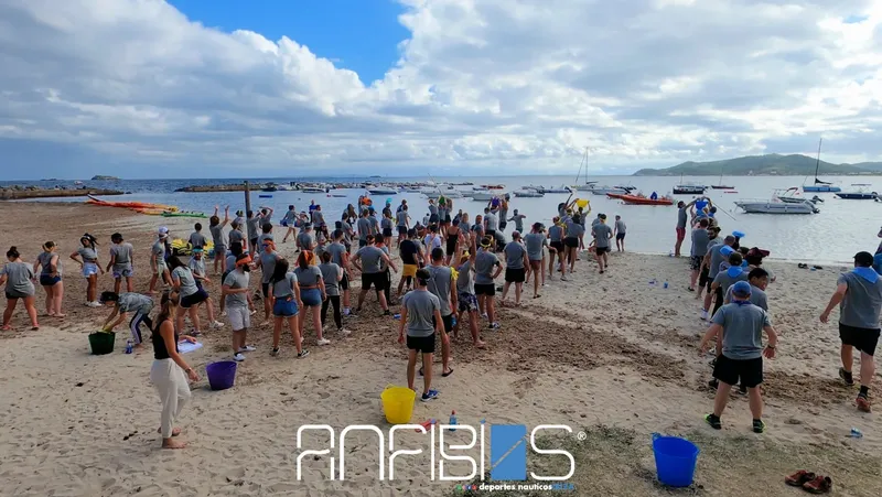 Groupe de personnes sur une plage, devant des bateaux amarrés