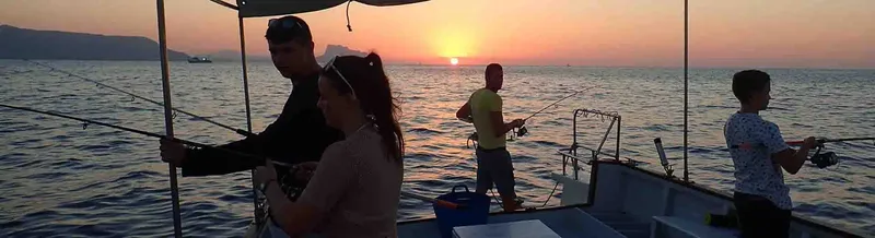 Quatre personnes pêchant sur un bateau en mer au coucher du soleil