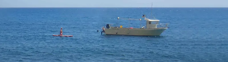 Personnes dans l'eau près d'un bateau de plongée en mer bleue