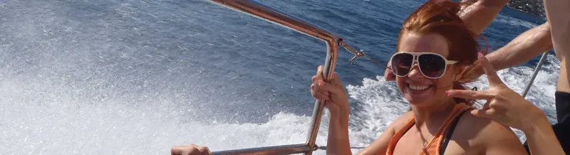Femme souriante sur un bateau en mouvement, lunettes de soleil
