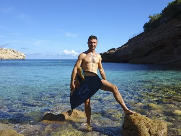 Un homme torse nu, en maillot de bain, pose sur des rochers