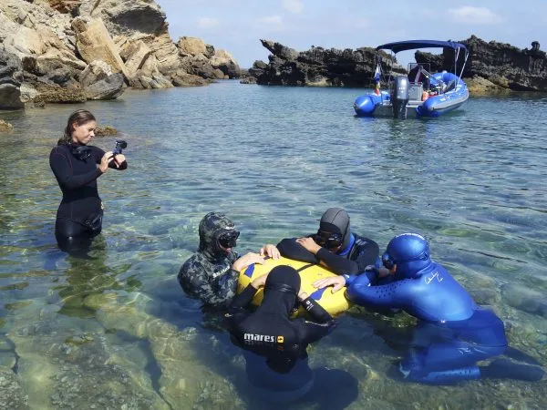Plongée : instructeur et élèves en combinaison près d'un bateau