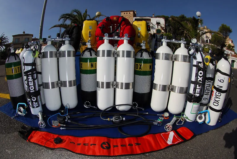 Bouteilles de plongée alignées avec détendeurs et accessoires sur tapis