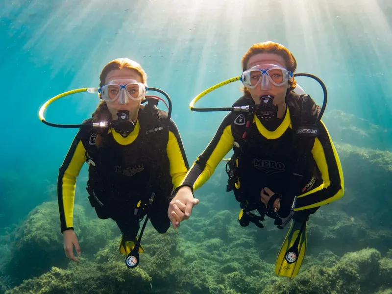 Deux plongeuses souriantes se tiennent la main sous l'eau
