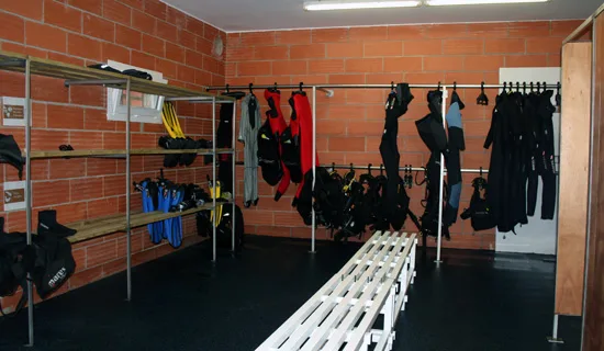 Vestiaire du centre de plongée avec combinaisons et équipements suspendus